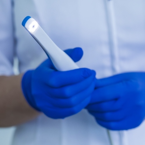 Dental professional holding a thin white intraoral camera