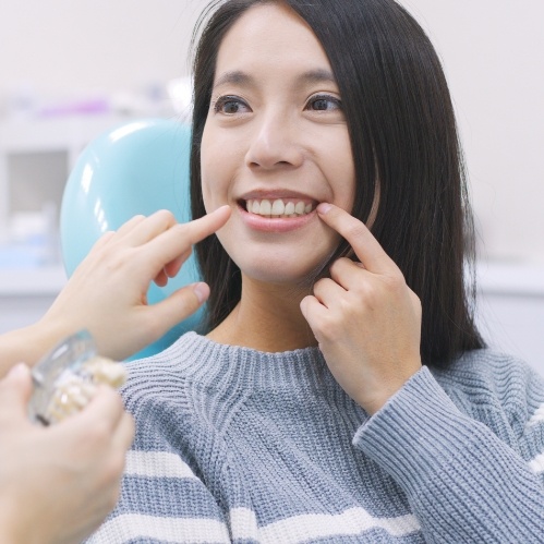 Woman in dental chair pointing to her tooth