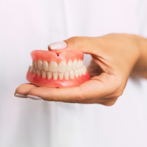 Dentist holding a set of dentures in Carrollton
