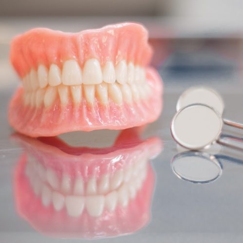 Full dentures on tray next to dental mirrors