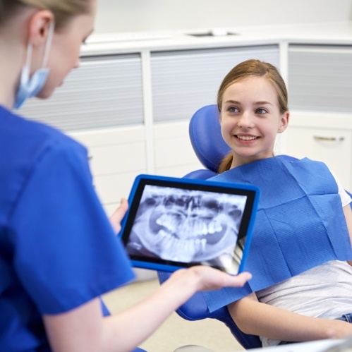 Dentist holding tablet with dental x ray while talking to a patient