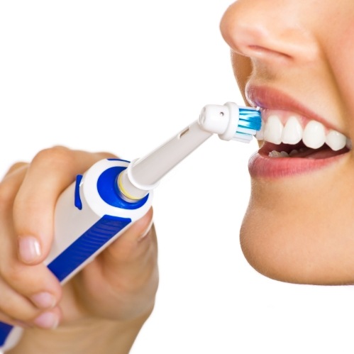 Close up of person using an electric toothbrush