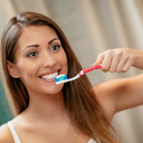 Woman smiling while brushing her teeth