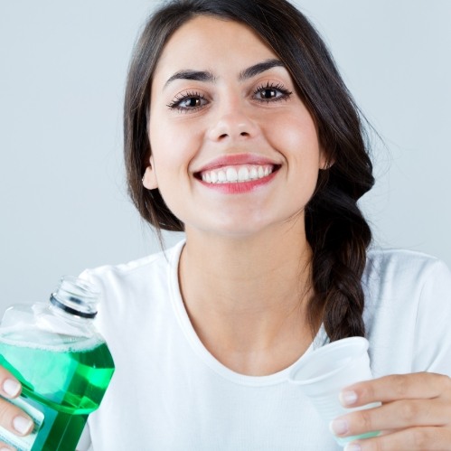 Smiling woman holding bottle of mouthwash