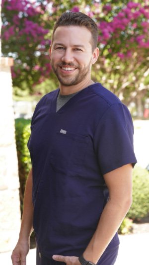 Carrollton Texas dentist Doctor Jordan smiling in dark blue scrubs