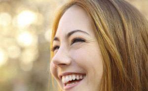 Woman with long brown hair smiling outdoors