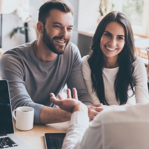 Man and woman smiling at person across desk