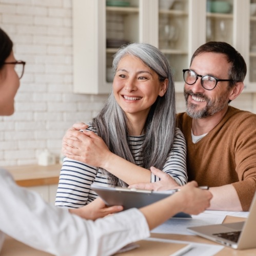 Older man and woman smiling at person across table