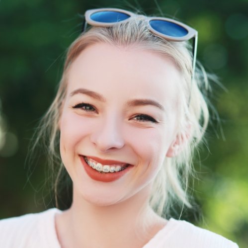 Young woman with braces grinning outdoors