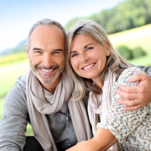 Man and woman hugging each other outdoors after receiving dental services in Carrollton