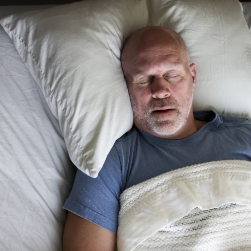 Older man sleeping on his back with his mouth open