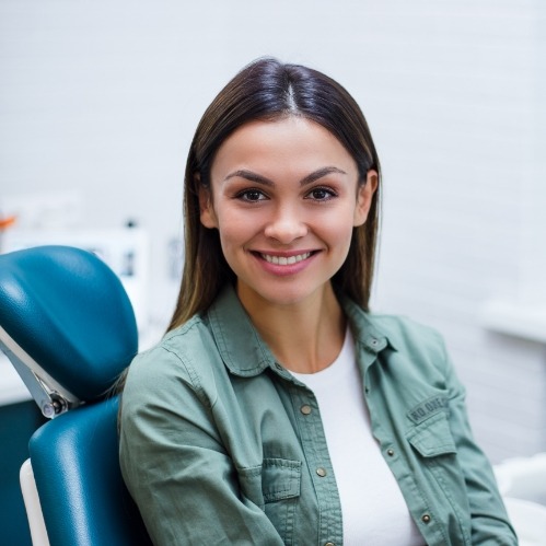 Woman in green shirt smiling in dental chair